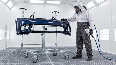 Lackierer im BUWO TwinShade-Anzug neben einem Universalständer in einer Lackierkabine